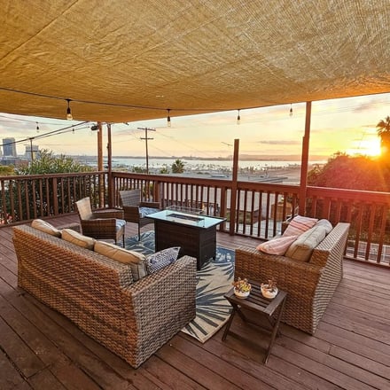 Skyline Hot Tub Deck wicker sofa seating with fire table and San Diego harbor at sunset