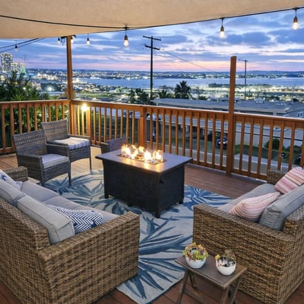 Fire table deck with wicker seating and San Diego city lights at dusk