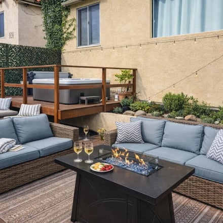 Hot Tub Skyline Deck fire table patio with blue-cushion sofas, wine glasses and hot tub beyond